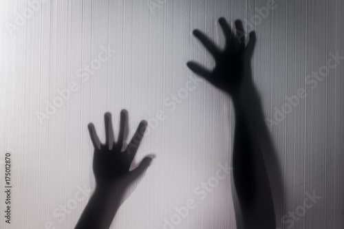 Halloween hands behind transparent glass blur background as silhouette