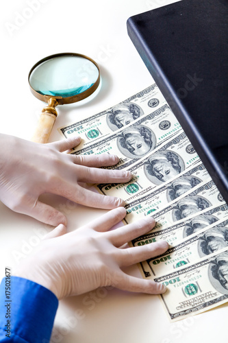 Hands in gloves check dollar bills on detector