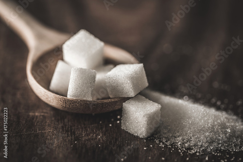 Photo Close up the sugar cubes and cane in wooden spoon on the table ,retro color tone