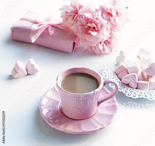 Pink cup with coffee, marshmallows hearts, gift and bouquet of pink roses on a white background.Top view. .Holiday concept