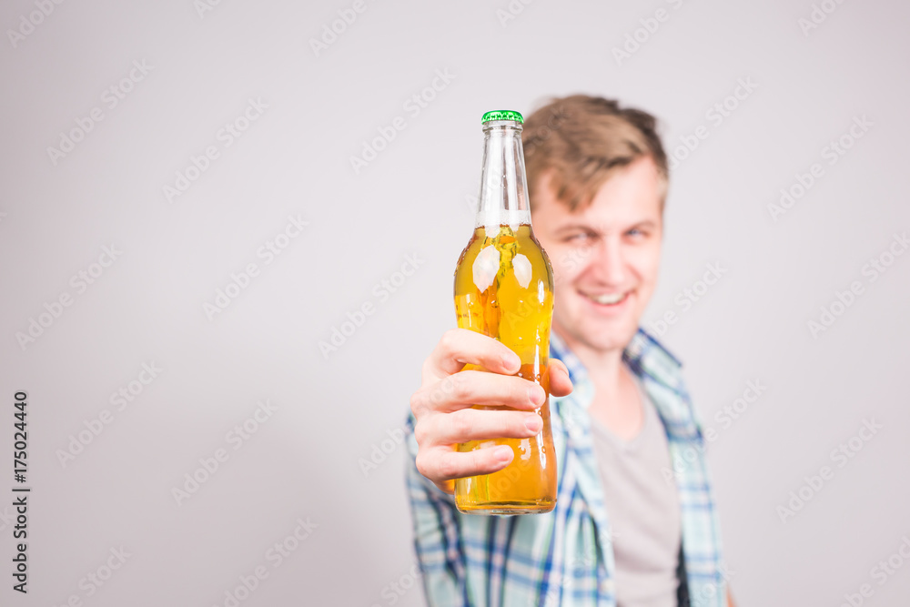 Happy young cheerful man holding beer, on grey background with copy space Happy young cheerful man holding beer, on grey background with copy space