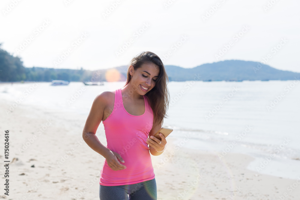Portrait Of Young Woman Runner On Beach Holding Cell Smart Phone While Jogging On Seaside Female Happy Smiling Girl Sport Runner Healthy Lifestyle Concept Portrait Of Young Woman Runner On Beach Holding Cell Smart Phone While Jogging On Seaside Female Happy Smiling Girl Sport Runner Healthy Lifestyle Concept