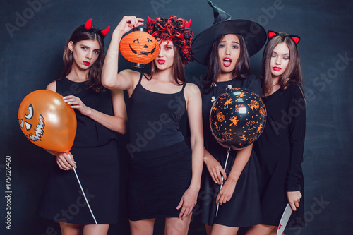 Women in halloween costumes standing with a balloons.