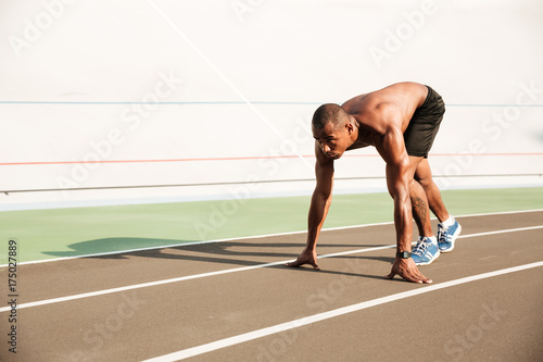 Young musculary african sports man in starting position ready to start