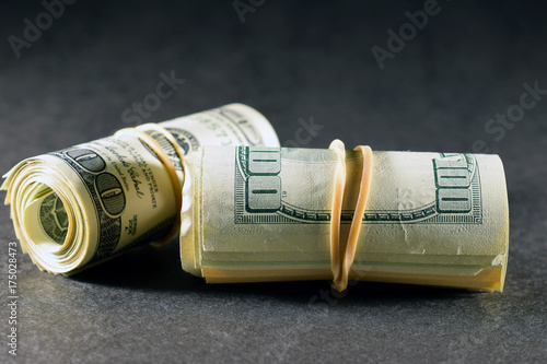 Money rolls on dark surface and background. Horizontal image.