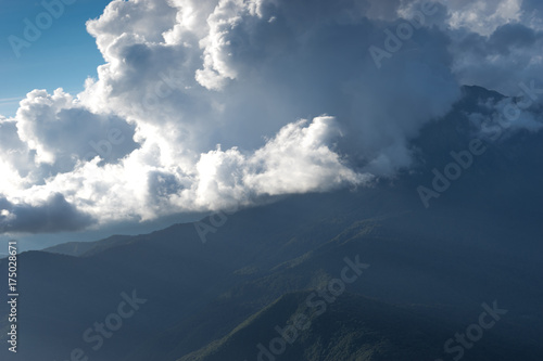 mountain landscape on the blue sky background and white clouds with sun rays