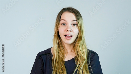 Shocked woman. Young woman touching face with hands and staring at camera while standing against white background