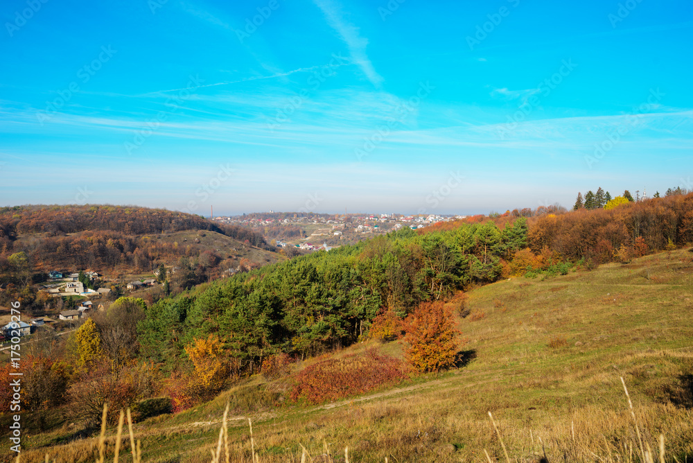 Naklejka premium View on the beautiful colorful autumn landscape of the hills with trees and greenfields in the countryside