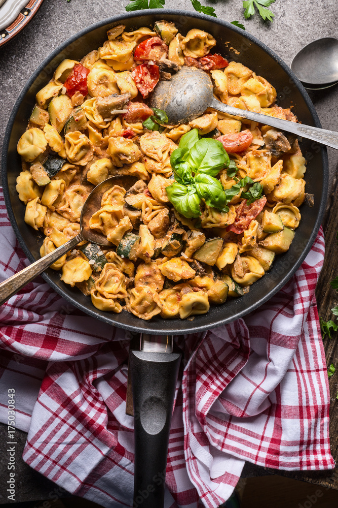 Vegetarian tortellini pot with vegetables sauce and spoons , top view, close up. Healthy cooking and eating. Italian food concept