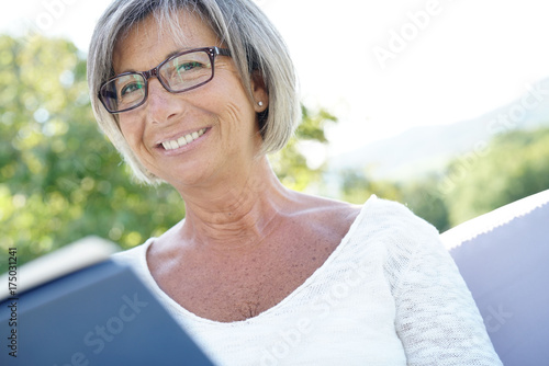 Free Download Senior woman with eyeglasses reading book in outdoor sofa - GFXLoad