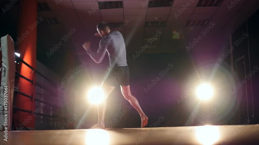 A boxer trains on an empty gym floor under spotlights. A boxer trains on an empty gym floor under spotlights.