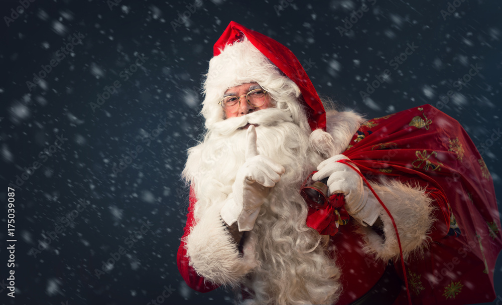 Santa Claus making a silence gesture, on dark background Santa Claus making a silence gesture, on dark background
