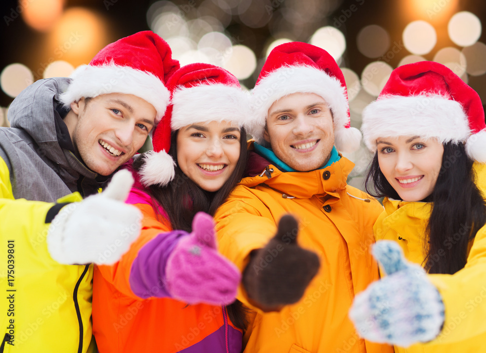 happy friends in santa hats and ski suits outdoors happy friends in santa hats and ski suits outdoors