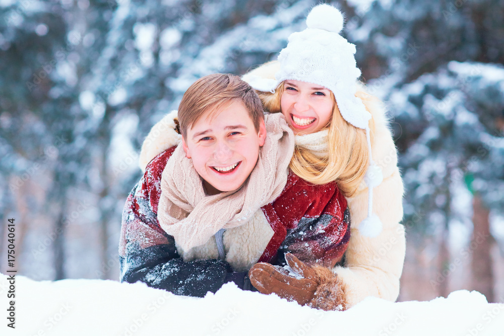 Portrait of a happy couple laughing in the snow in a winter park.