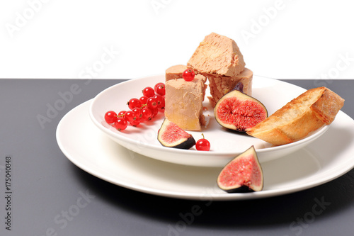 foie gras with croutons, figs and redcurrant. in a white plate, on a marble table