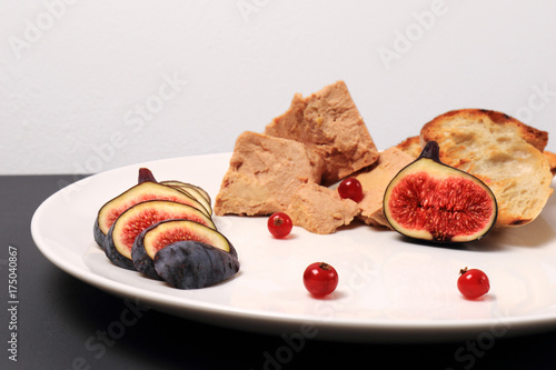 foie gras with croutons, figs and redcurrant. in a white plate, on a marble table. copy space © oleh91