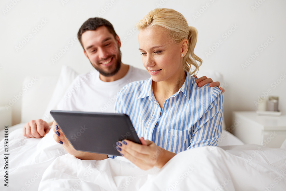 smiling happy couple with tablet pc in bed at home smiling happy couple with tablet pc in bed at home