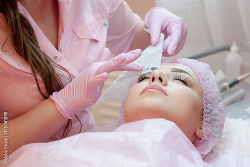A young woman lies and gets a make-up of her eyebrows in a beauty salon. The use of permanent makeup on the eyebrows. The master works with the eyebrows. Semi-permanent makeup
