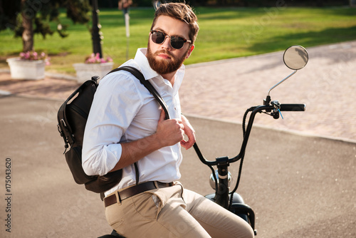 Side view of Calm bearded man in sunglasses with backpack