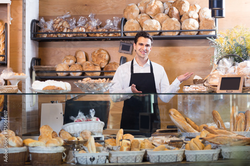 Male bakery employee offering bread and pastry