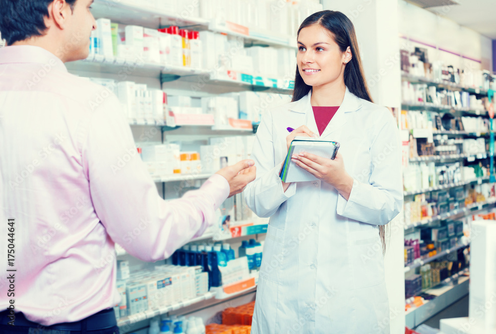 Pharmacist and customer in drugstore .