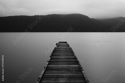 Wooden jetty and flat calm lake, dark low light 