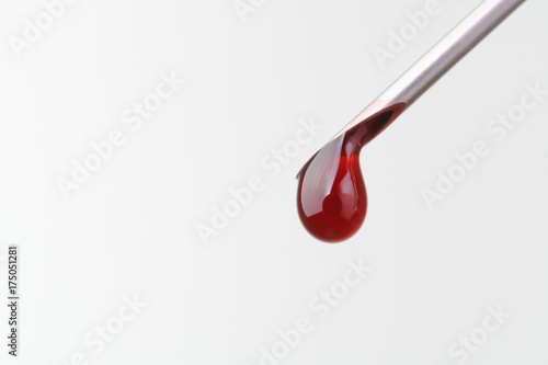 Drop of blood falling from syringe on white background, Macro shot
