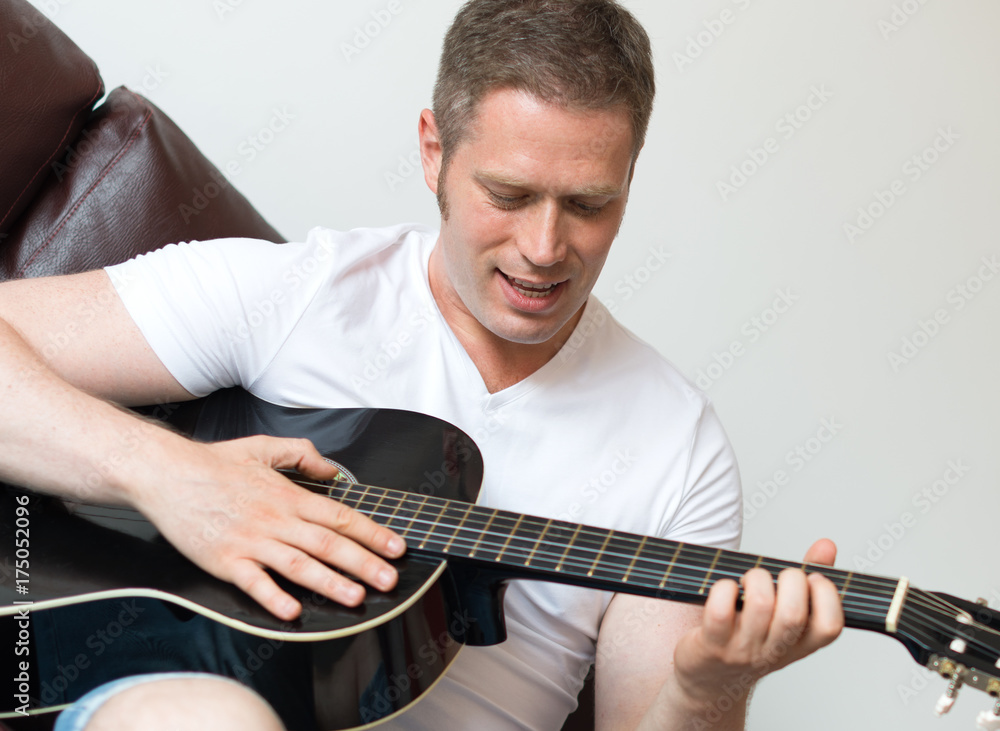 Obraz premium Handsome man playing guitar at home.