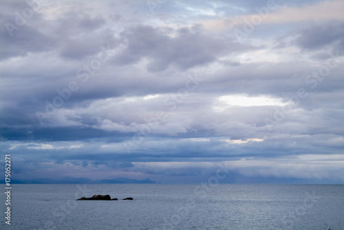 Gloomy day sea landscape with a rainy cloudy sky. Bay and rocks at background. Horizontal frame