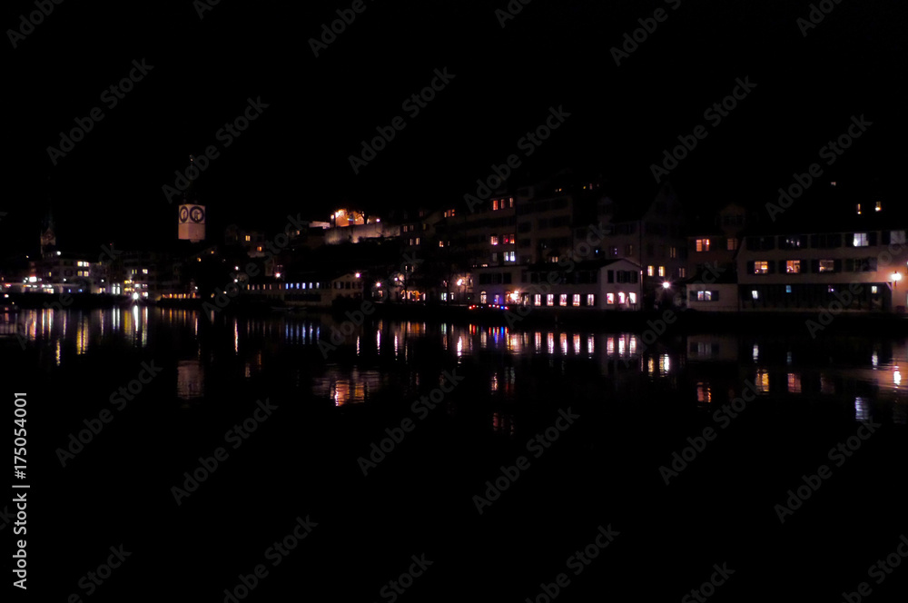 Night city near the river with reflection of buildings in the water