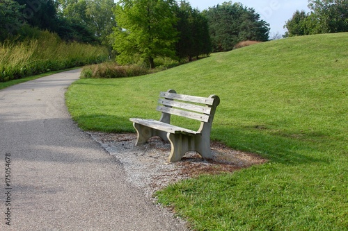 A empty park bench on the hill in the parks landscape.