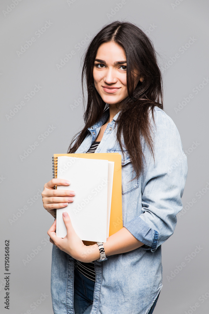 Portrait of young student holding a book over grey background Portrait of young student holding a book over grey background
