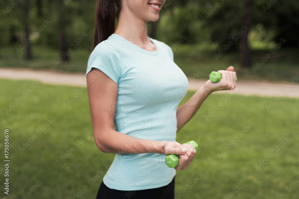 Girl in the park doing exercises with dumbbells Girl in the park doing exercises with dumbbells