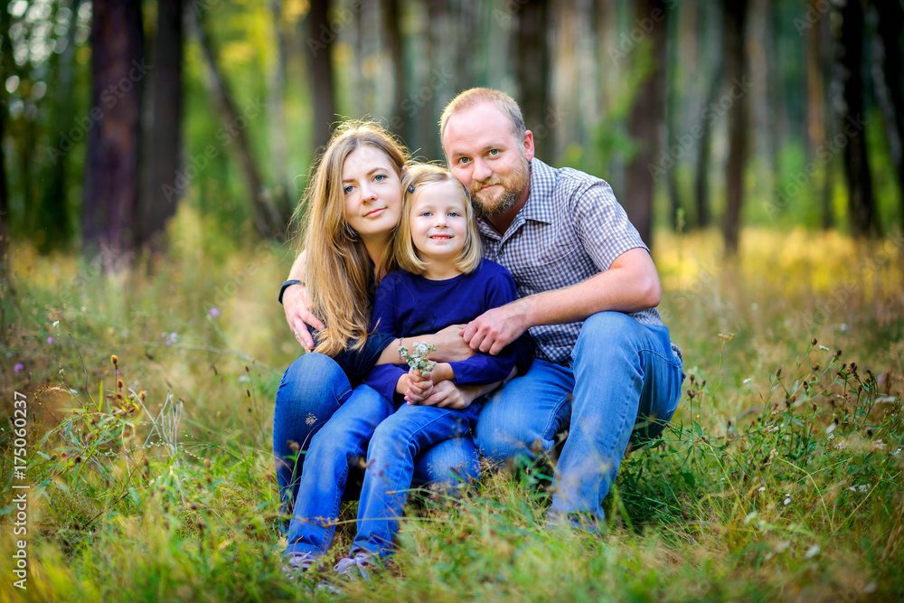 .happy family walks in the park, hug each other and look at the camera, the girl is holding a bouquet of wildflowers in her hands .happy family walks in the park, hug each other and look at the camera, the girl is holding a bouquet of wildflowers in her hands