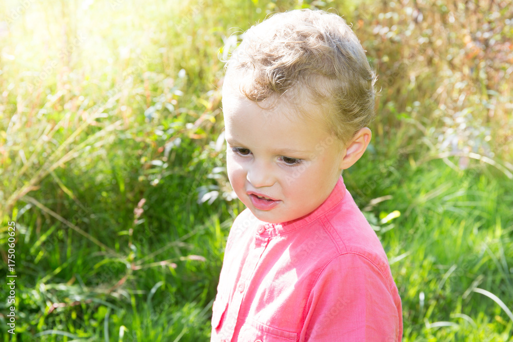 Happy cute kid boy in colorful clothes playing in summer garden Happy cute kid boy in colorful clothes playing in summer garden