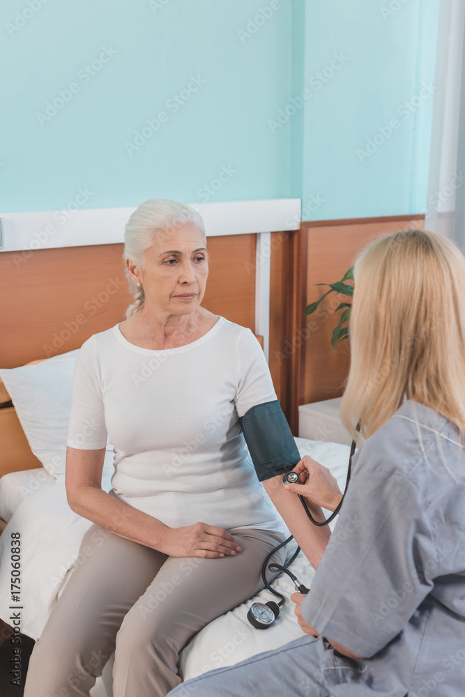 Obraz premium nurse measuring blood pressure to patient