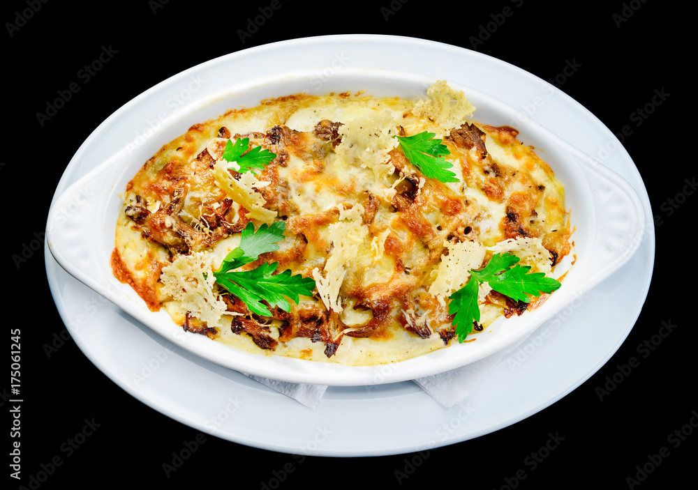 Tasting and appetizing traditional Italian lasagna dish with mushrooms served with fresh dill in a white plate isolated on black background. Autumn menu in an Italian restaurant
