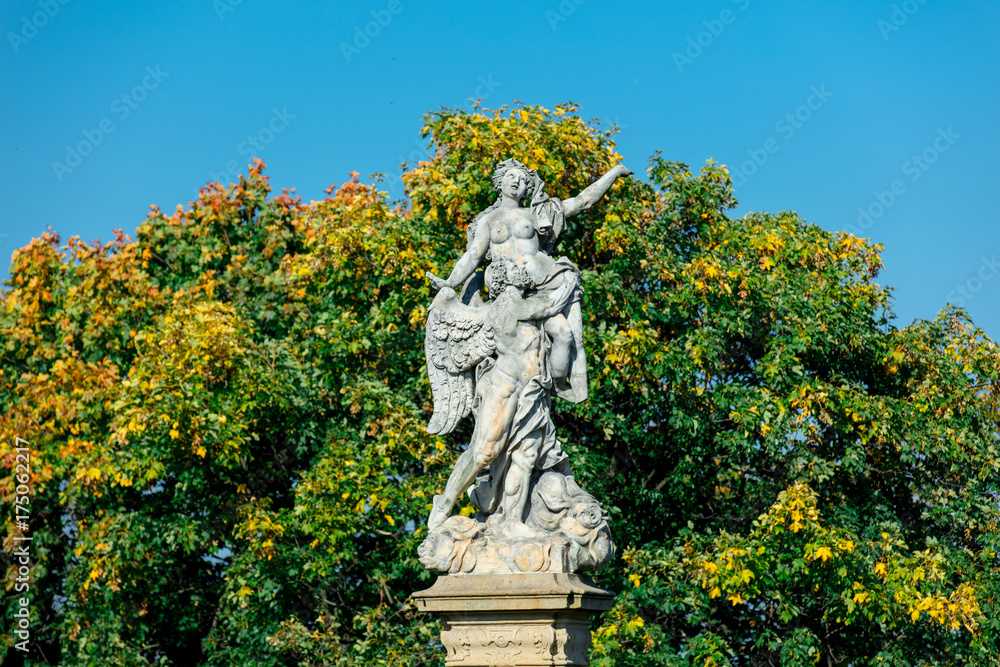 Fototapeta premium Classic statue in a park with blue sky and tree on background