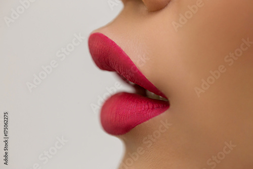 Beautiful open mouth  profile  bright red lipstick  white background  close-up  dark  clear skin  whispers  speaks  cosmetics