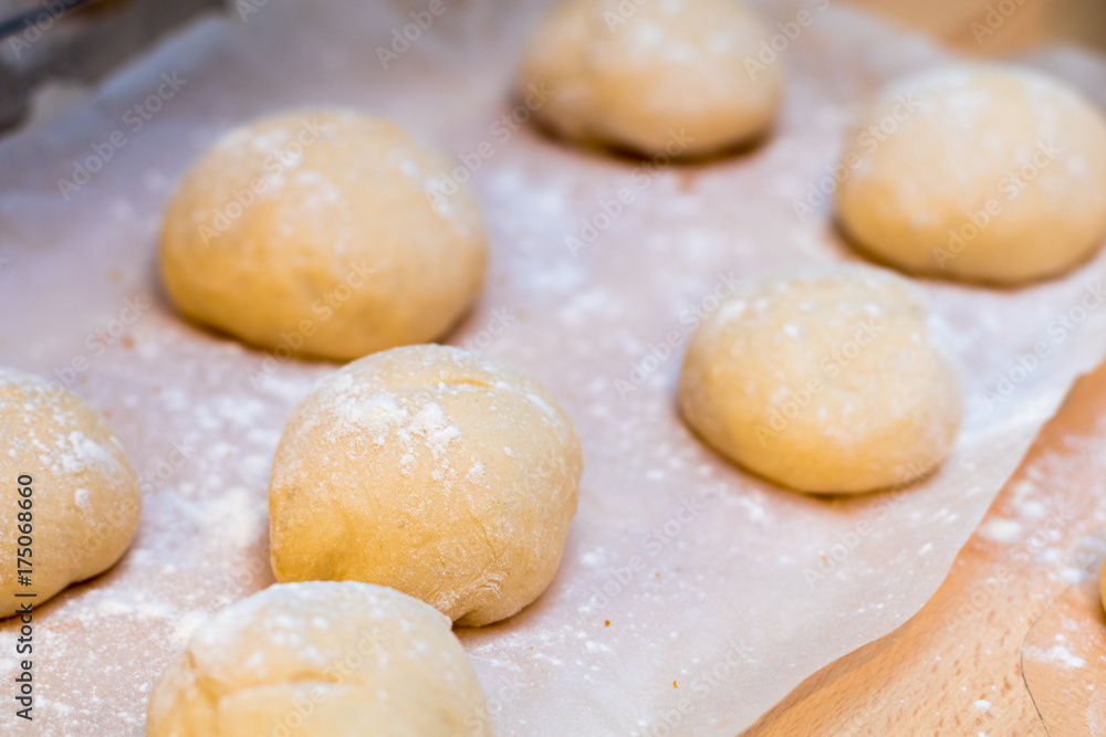 Authentic home kitchen, freshly made white bread rolls proving sprinkled with with flour ready for baking on tray