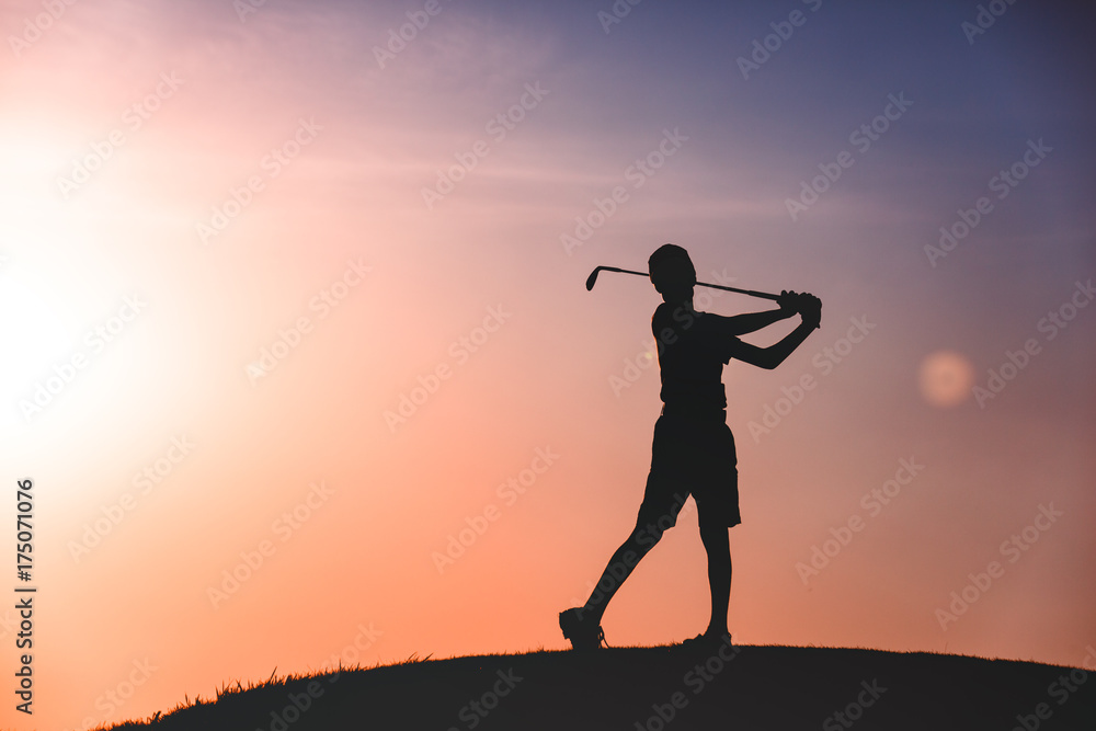 silhouette of boy golfer with golf club at sunset