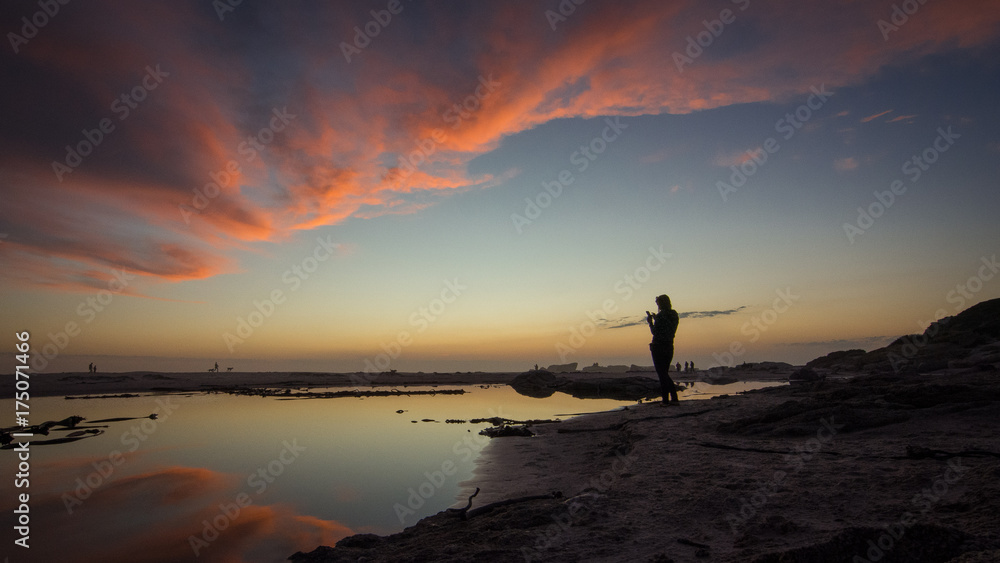 Next to the lagoon on Noordhoek Beach, a photographer watches the sunset