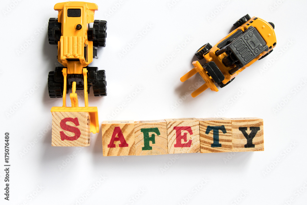 Toy plastic bulldozer hold toy block letter s to fulfill word safety with foklift on white background Toy plastic bulldozer hold toy block letter s to fulfill word safety with foklift on white background