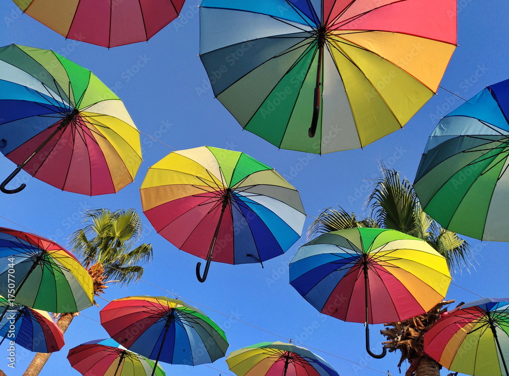 Multicolored umbrellas against the sky in the backlight