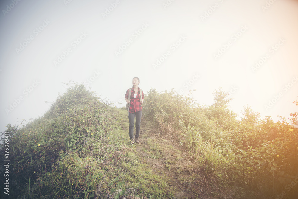 Hipster young girl with backpack enjoying sunset on peak of foggy mountain. Tourist traveler on background view mockup. Hiker looking sunlight in trip