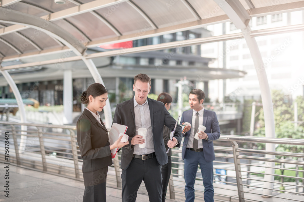 Business colleagues walking outside office & talking to each other. Businessman talk and hold coffee cup Business colleagues walking outside office & talking to each other. Businessman talk and hold coffee cup