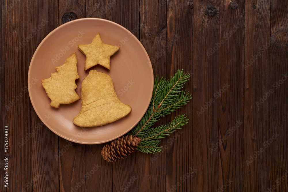 Fototapeta premium homemade cookies in the form of spruce, stars, bells on a pink plate on a wooden background.