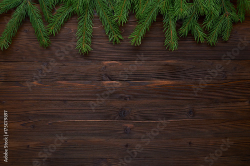 New Year's background of fir branches and a brown wooden background for congratulations