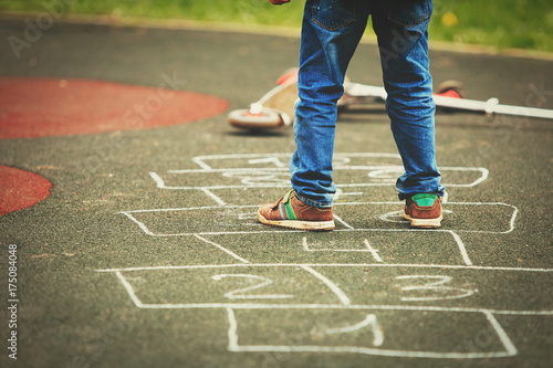 little boy playing hopscotch on playground