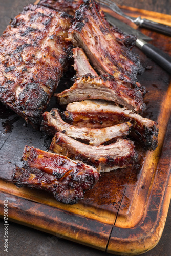 Barbecue pork spare ribs as top view on a burnt cutting board